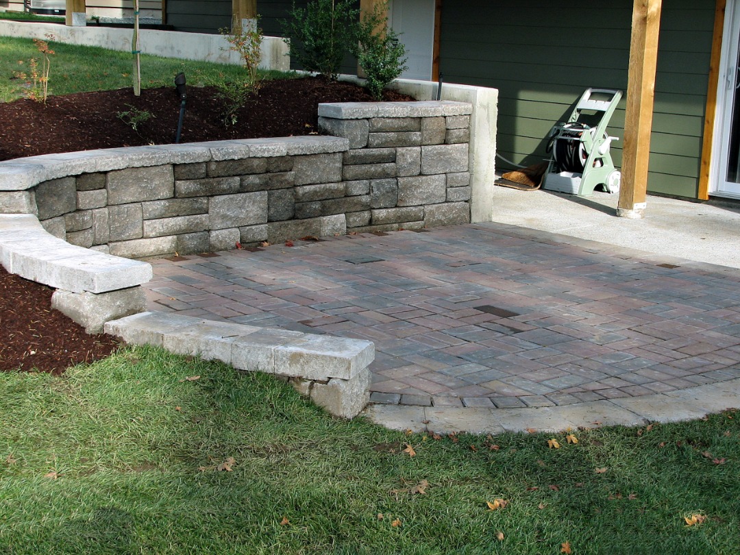 A well - crafted retaining wall with a paver patio as well.