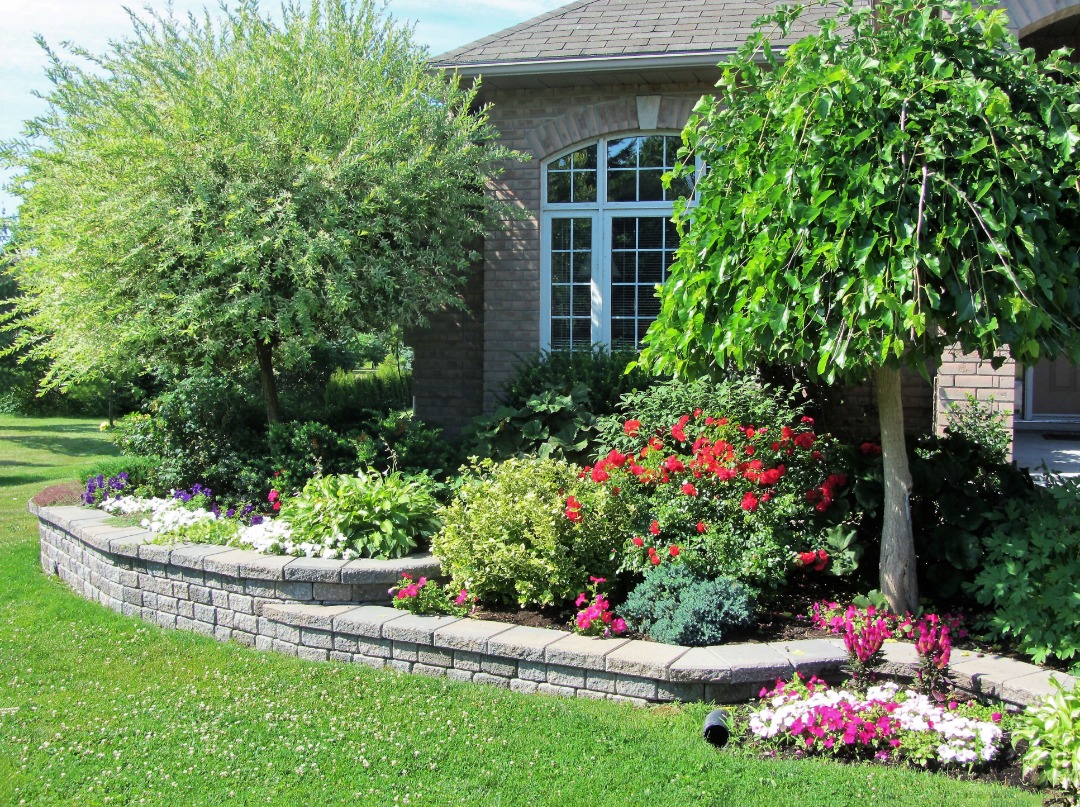 A perfect retaining wall in front of a home with amazing flowers.